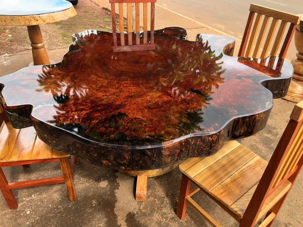 Uma mesa de madeira com resina. Quatro cadeiras de madeira ao redor.