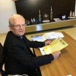 Imagem Dom João Wilk sentado segurando informativo