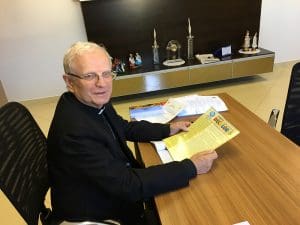 Imagem Dom João Wilk sentado segurando informativo