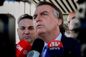 Imagem Jair Bolsonaro concedendo entrevista, microfones estão em frente Bolsonaro