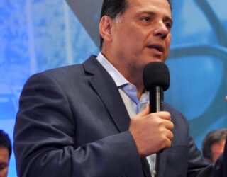 Imagem Marconi Perillo falando, ele segura o microfone