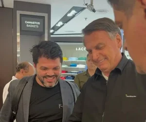 Imagem Márcio e Jair Bolsonaro, eles estão sorrindo e olhando para baixo