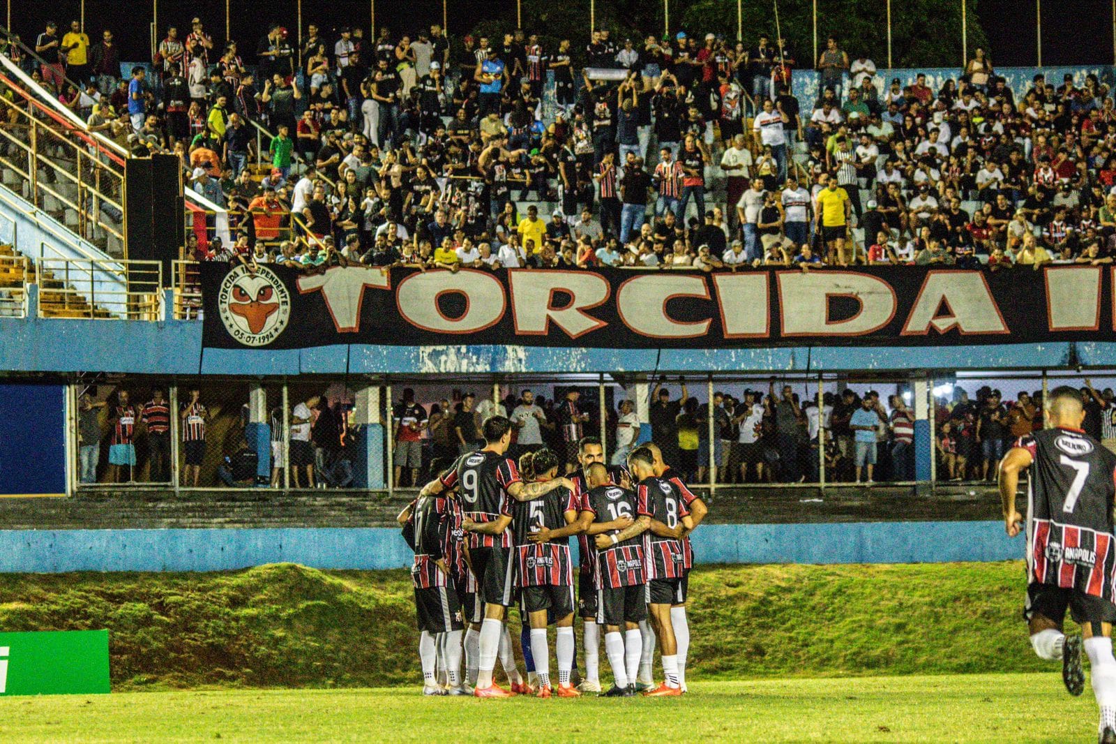 Imagem jogadores abraçados em frente a torcida