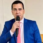 Imagem Hélio Lopes com microfone na mão, ele está com terno azul e gravata cor de rosa