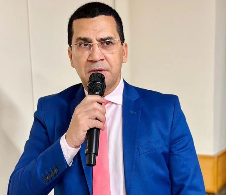 Imagem Hélio Lopes com microfone na mão, ele está com terno azul e gravata cor de rosa