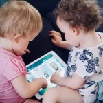Imagem de dois bebes vendo uma tela de tablet