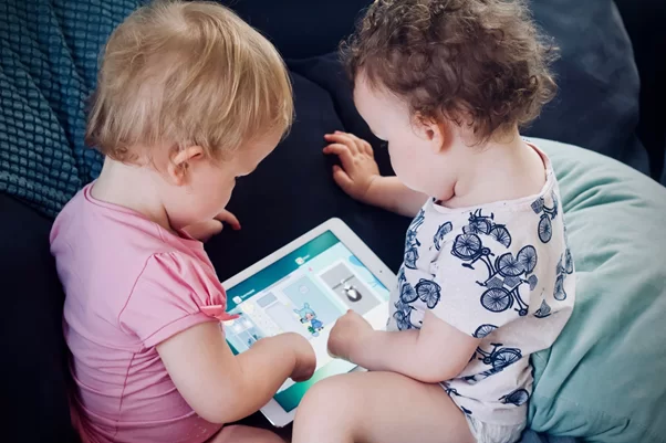 Imagem de dois bebes vendo uma tela de tablet