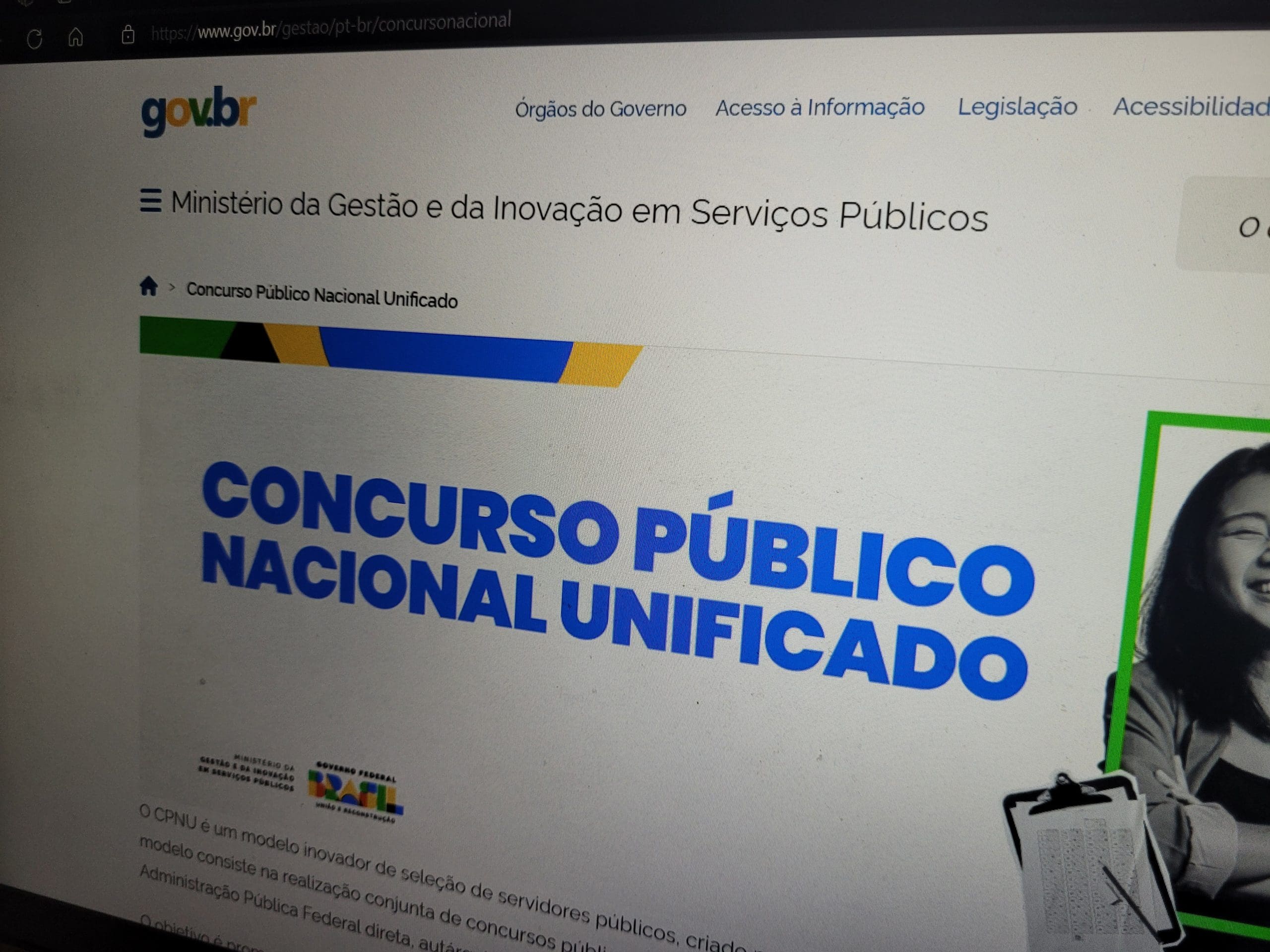 Uma tela de computador é vista de perto. Letras maiúsculas azuis dizem "concurso público nacional unificado". É possível ver o logo do Gov.br, colorido.