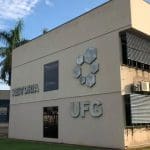 A imagem mostra um prédio bege com letreiros que dizem "Reitoria" e "UFG", além da logo com hexágonos da universidade.