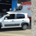 A imagem está dividida em duas. À esquerda, um carro branco está em destaque. Há uma viatura da polícia e uma do Samu atrás. À direita, um chão de brita tem duas manchas de sangue.