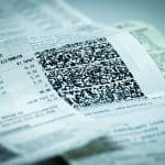 A imagem mostra uma nota fiscal, com foco no código QR. É possível ler o preço de alguns itens, mas o nome dos produtos está cortado da foto.