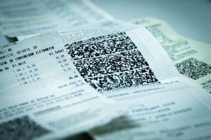 A imagem mostra uma nota fiscal, com foco no código QR. É possível ler o preço de alguns itens, mas o nome dos produtos está cortado da foto.