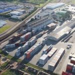 Uma área de logística é vista por cima, com diversos contêineres.