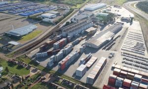 Uma área de logística é vista por cima, com diversos contêineres.