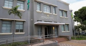 Um prédio cinza é visto pela frente. Letras pequenas na fachada dizem "Tribunal Regional Eleitoral do Governo de Goiás".