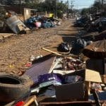 Rua está cheia de destroços, resultantes das enchentes.