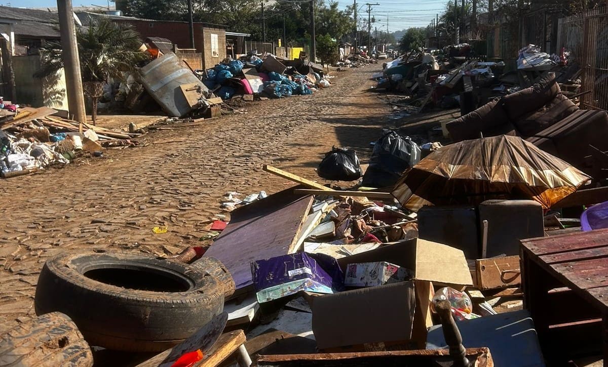 Rua está cheia de destroços, resultantes das enchentes.
