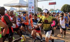 Várias pessoas correm na largada de uma corrida. Elas vestem roupas esportivas.