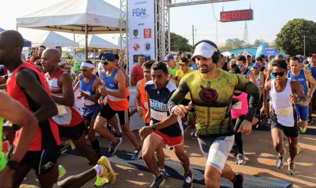 Várias pessoas correm na largada de uma corrida. Elas vestem roupas esportivas.