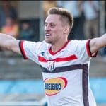 Ariel, jogador do Anápolis FC, comemora gol com os braços levantados.