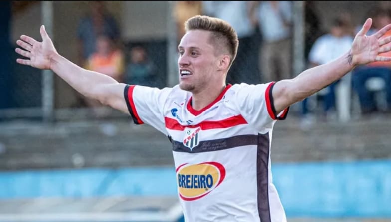 Ariel, jogador do Anápolis FC, comemora gol com os braços levantados.