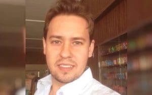 Christiano Mamedio sorri para a câmera enquanto tira uma selfie. Ele é um homem branco de cabelos claros.