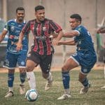 Kevyn, jogador do Anápolis, conduz a bola enquanto dois jogadores do Iguatu tentam tomá-la.