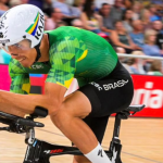 O ciclista Carlos Alberto pedala em uma competição. Ao fundo, a plateia desfocada.