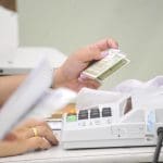 Mesário confere informações de eleitor junto à máquina de biometria.