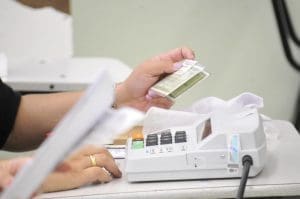 Mesário confere informações de eleitor junto à máquina de biometria.