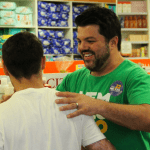 Márcio Corrêa cumprimenta apoiador dentro de um comércio.