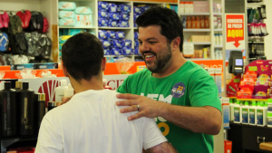 Márcio Corrêa cumprimenta apoiador dentro de um comércio.