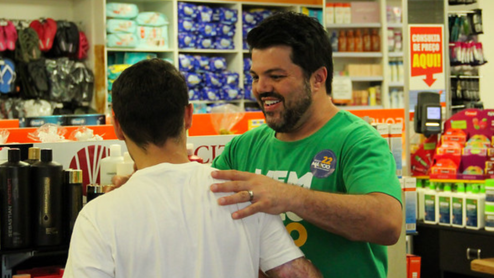 Márcio Corrêa cumprimenta apoiador dentro de um comércio.