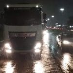 Um caminhão e um carro estão na estrada à noite, enquanto chove.