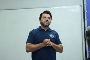 Márcio Corrêa está em pé, enquanto fala com as mãos juntas.