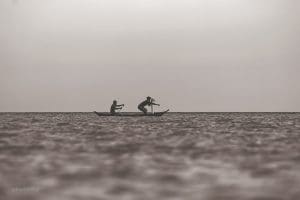 Imagem fotografia de dois homens remando em um barco na aguá