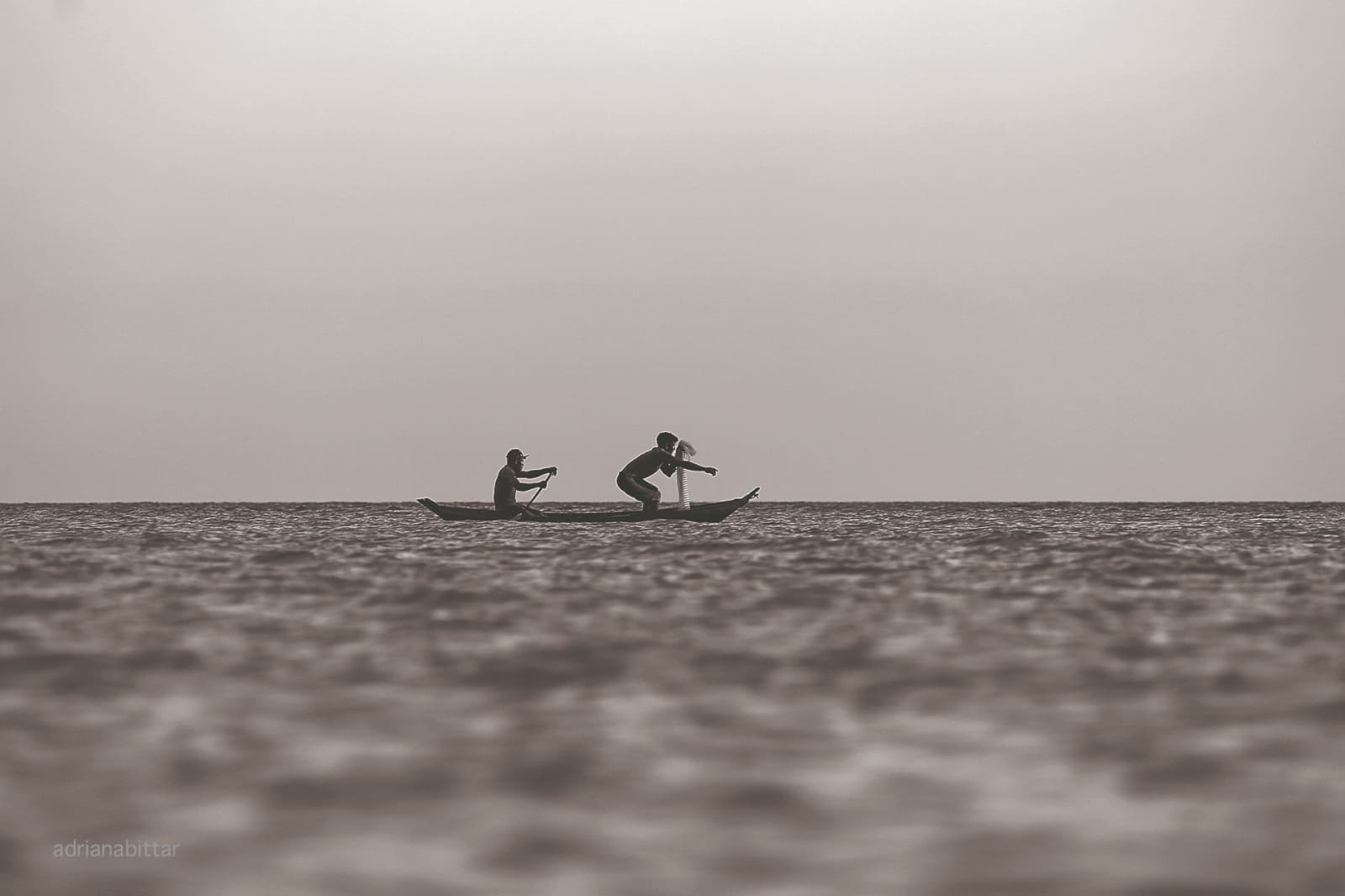 Imagem fotografia de dois homens remando em um barco na aguá
