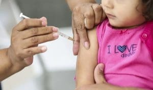 Uma menina pequena recebe uma dose de vacina injetável.
