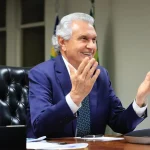 Imagem Ronaldo Caiado sentado sorrindo de braços abertos