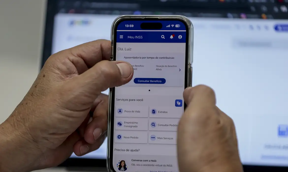 Imagem mão segurando celular com o aplicativo Meu INSS aberto