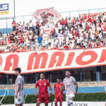 Imagem torcedores no estádio Jonas Duarte, a frente aparecem jogadores da Anapolina e do Tupy de Jussara
