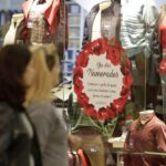 Imagem duas mulheres olhando para uma estante com roupas e um cartaz do dia dos namorados