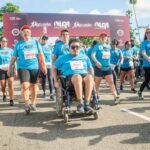 Imagem Corrida da Inclusão, a frente um cadeirante, atrás pessoas caminham