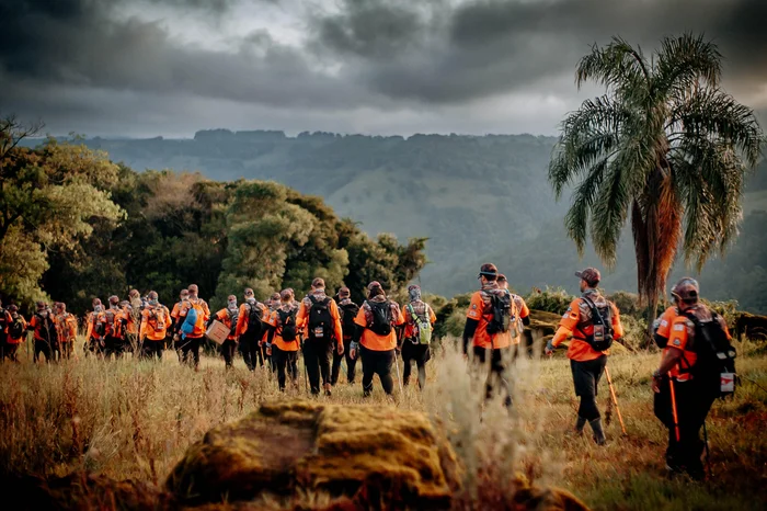 Imagem homens caminhando em área rural com mata