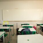 Imagem Sala de aula vazia, carteiras estão com mochilas em cima