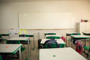 Imagem Sala de aula vazia, carteiras estão com mochilas em cima