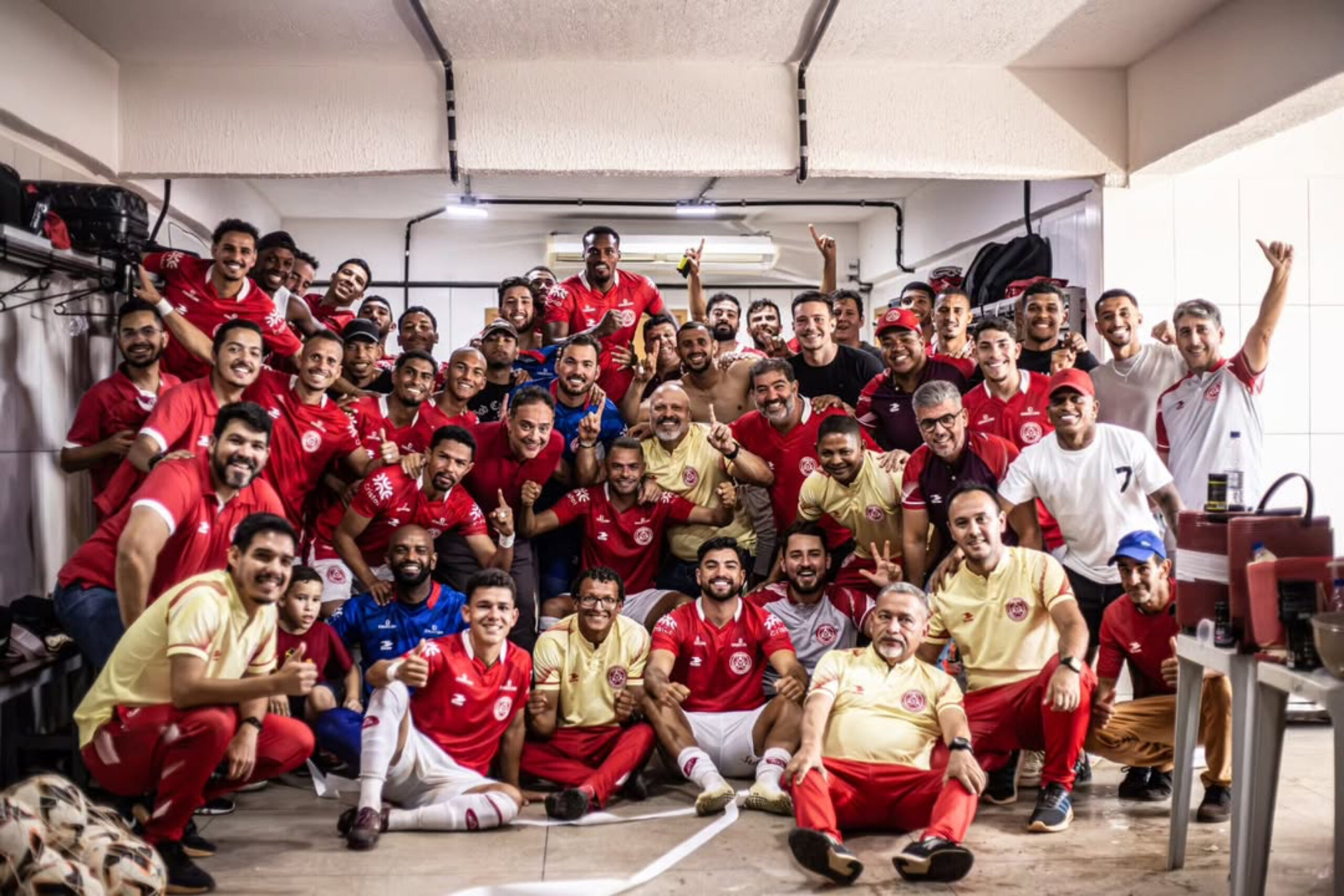 Imagem time da Anapolina no vestiario, jogaores e comissão ténico sorrindo após vitória no Jonas Duarte