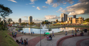 A imagem mostra o Parque Ipiranga, lago, pessoas e prédios em volta