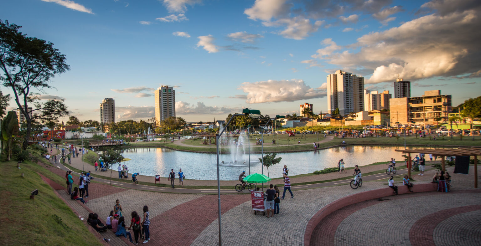 A imagem mostra o Parque Ipiranga, lago, pessoas e prédios em volta