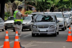 Imagem blitz parando carro, policial militar sinaliza para carro encontrar na rua